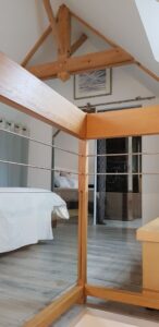 Charpente apparente et garde-corps en bois de la mezzanine du gîte