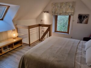 Chambre parentale en mezzanine avec fenêtres de toit et garde-corps en bois