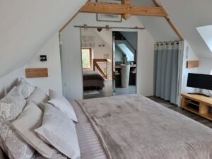 Chambre parentale du gîte avec grand lit, téléviseur et salle d'eau attenante