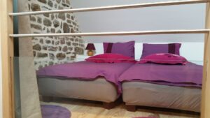 Chambre enfant en mezzanine avec deux couchages et mur de pierre apparente