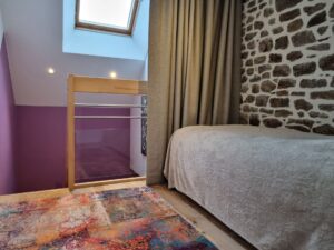 Chambre enfant en mezzanine, mur de pierre apparente et fenêtre de toit