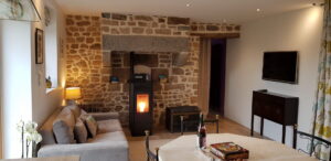 Séjour avec cheminée en pierre, poêle à granulés et table de repas, gîte de La Filuzière