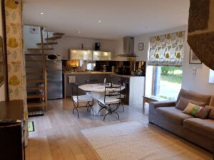 Pièce de vie ouverte du gîte 4 étoiles : coin repas, cuisine équipée et escalier vers la mezzanine